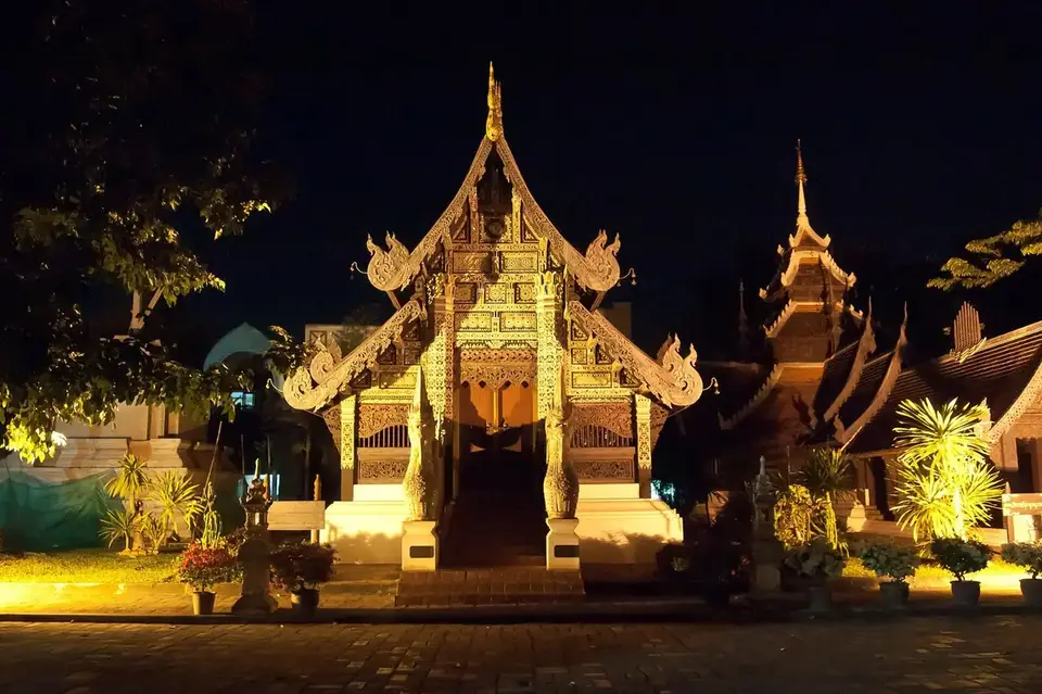 A carved Lanna temple hall at Wat Chedi Luang in Chiang Mai's old city, lit up at night