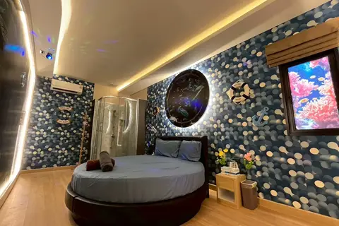 Pink X Station: room with a round bed and mosaic wall with a moon light