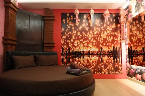 Pink X Station: room with a round bed and lantern-print wall